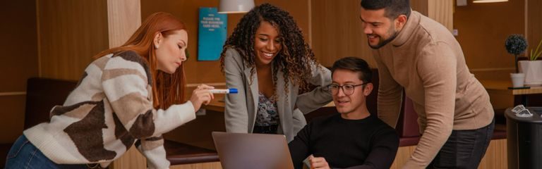 Laptop on a wooden desk next to a white chair and a mouse.